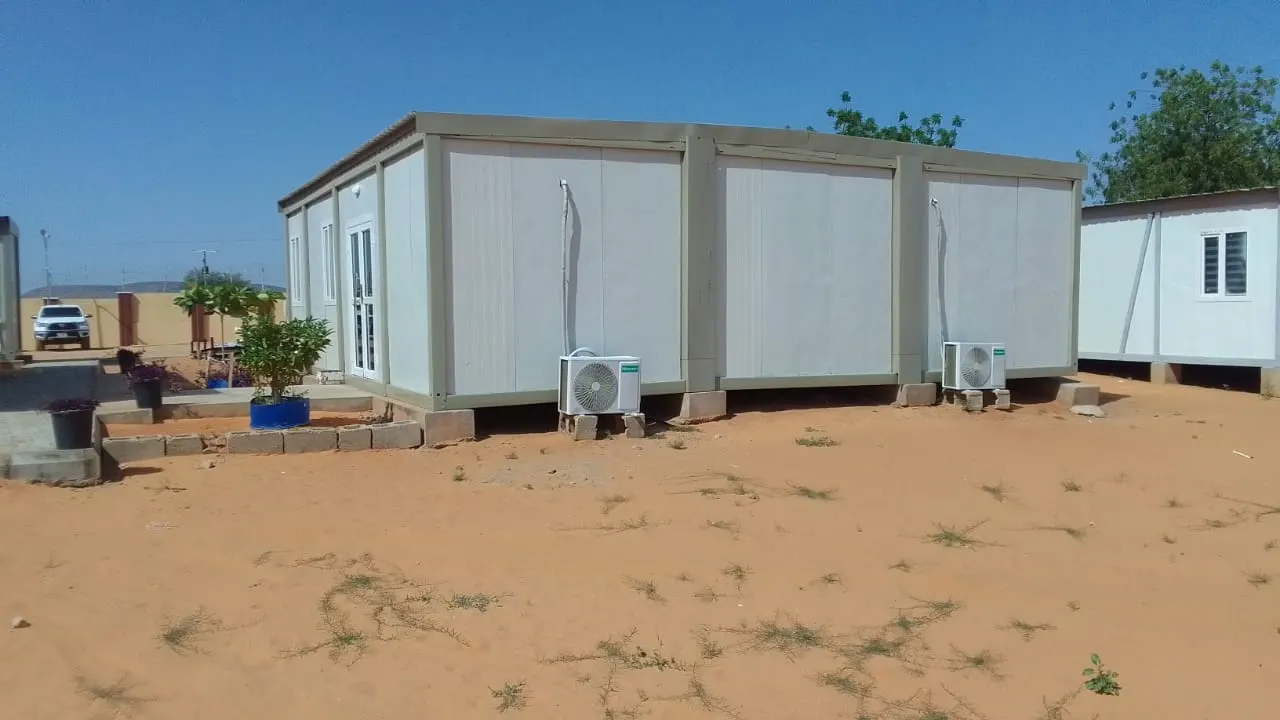 Row of connected white modular cabins installed on a prepared site